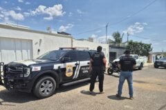 policiais civis ao lado de viatura da Polícia Civil e em frente de residência de investigado