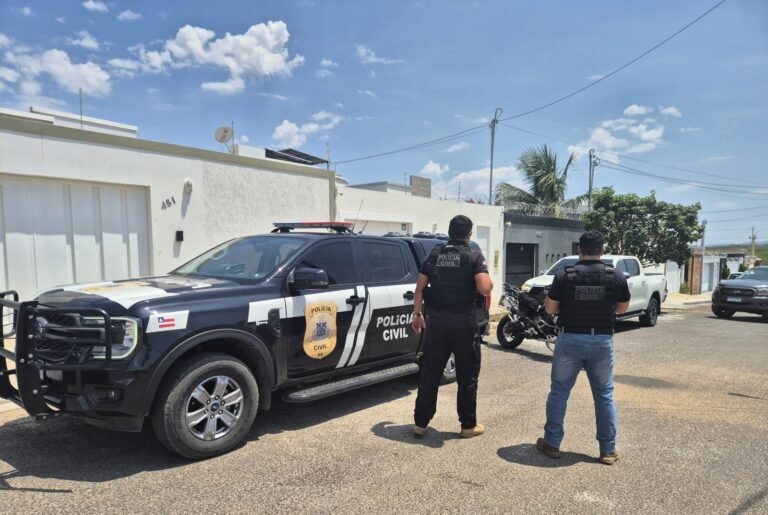 policiais civis ao lado de viatura da Polícia Civil e em frente de residência de investigado