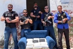 policiais ao lado de sofá que foi encontrado com drogas