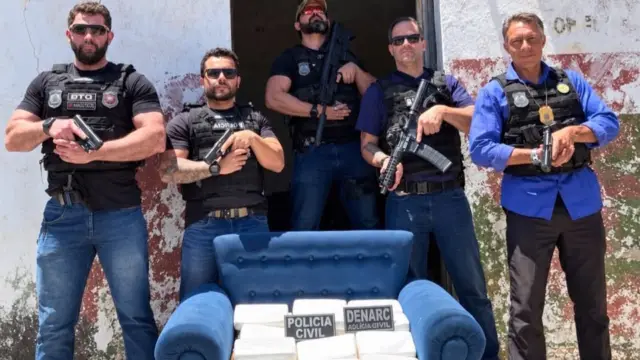 policiais ao lado de sofá que foi encontrado com drogas