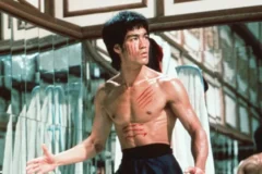Bruce Lee em cena de filme de artes marciais, com expressão séria