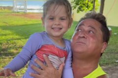 Maria Flor sorri ao lado do avô Leonardo, que a abraça